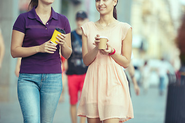 Image showing Beautiful girls holding paper coffee cup and enjoying the walk in the city