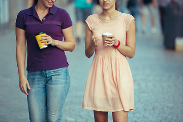 Image showing Beautiful girls holding paper coffee cup and enjoying the walk in the city