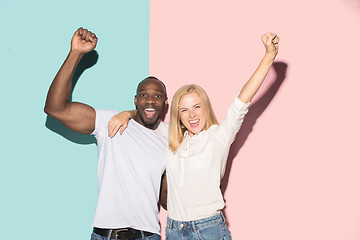 Image showing We won. Winning success happy afro man and woman celebrating being a winner. Dynamic image of caucasian female and male model on pink studio.