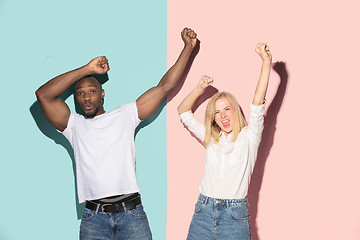 Image showing We won. Winning success happy afro man and woman celebrating being a winner. Dynamic image of caucasian female and male model on pink studio.