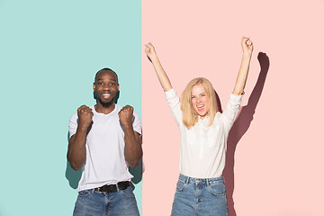 Image showing We won. Winning success happy afro man and woman celebrating being a winner. Dynamic image of caucasian female and male model on pink studio.