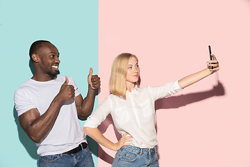 Image showing Mixed raced couple of students taking common selfie with phone. Caucasian girl and her African boyfriend posing at studio .