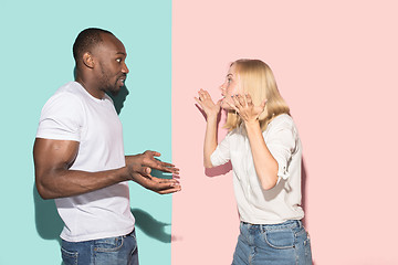 Image showing Beautiful female and male portrait on pink and blue studio backgroud. The young emotional couple