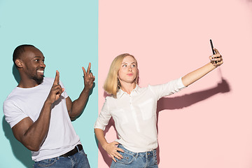 Image showing Mixed raced couple of students taking common selfie with phone. Caucasian girl and her African boyfriend posing at studio .