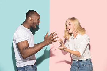 Image showing Beautiful female and male portrait on pink and blue studio backgroud. The young emotional couple