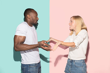 Image showing Beautiful female and male portrait on pink and blue studio backgroud. The young emotional couple