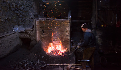 Image showing young traditional Blacksmith working with open fire