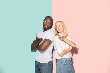 Image showing Beautiful female and male portrait on pink and blue studio backgroud. The young emotional couple