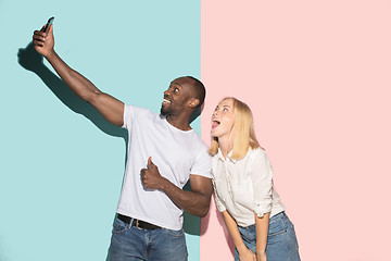 Image showing Mixed raced couple of students taking common selfie with phone. Caucasian girl and her African boyfriend posing at studio .