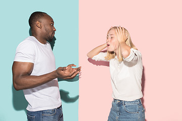 Image showing Beautiful female and male portrait on pink and blue studio backgroud. The young emotional couple