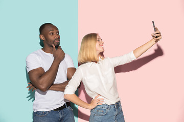 Image showing Mixed raced couple of students taking common selfie with phone. Caucasian girl and her African boyfriend posing at studio .