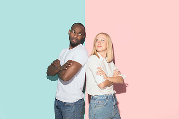 Image showing Beautiful female and male portrait on pink and blue studio backgroud. The young emotional couple