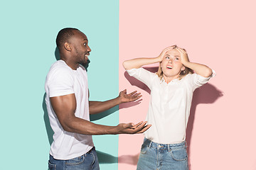 Image showing Beautiful female and male portrait on pink and blue studio backgroud. The young emotional couple