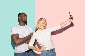 Image showing Mixed raced couple of students taking common selfie with phone. Caucasian girl and her African boyfriend posing at studio .