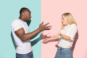 Image showing Beautiful female and male portrait on pink and blue studio backgroud. The young emotional couple