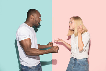 Image showing Beautiful female and male portrait on pink and blue studio backgroud. The young emotional couple