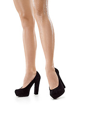 Image showing Tanned female legs in high heels isolated on white background.