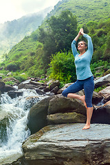 Image showing Woman in yoga asana Vrikshasana tree pose at waterfall outdoors