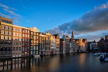 Image showing Hhouses and tourist boats on Amsterdam canal pier Damrak on suns