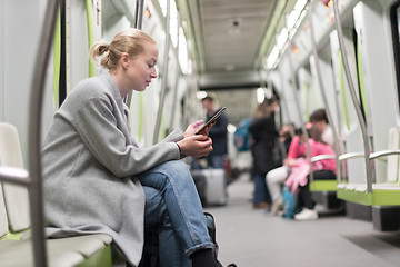 Image showing Beautiful blonde woman using smart phone while traveling by metro public transport.