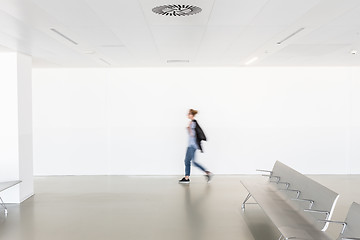 Image showing Motion blur of woman walking at contemporary white empty hallway