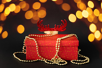 Image showing Christmas decoration gift box with hidden reindeer figure on bla