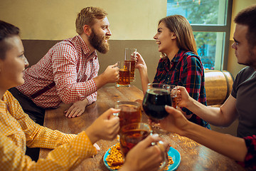 Image showing people, leisure, friendship and communication concept - happy friends drinking beer, talking and clinking glasses at bar or pub