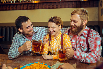 Image showing people, leisure, friendship and communication concept - happy friends drinking beer, talking and clinking glasses at bar or pub