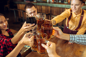 Image showing people, leisure, friendship and communication concept - happy friends drinking beer, talking and clinking glasses at bar or pub