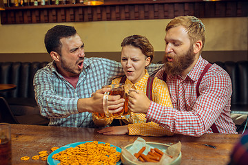 Image showing people, leisure, friendship and communication concept - happy friends drinking beer, talking and clinking glasses at bar or pub