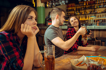 Image showing people, leisure, friendship and communication concept - happy friends drinking beer, talking and clinking glasses at bar or pub