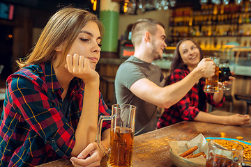 Image showing people, leisure, friendship and communication concept - happy friends drinking beer, talking and clinking glasses at bar or pub