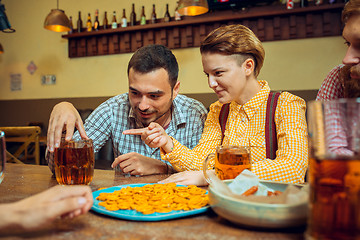 Image showing people, leisure, friendship and communication concept - happy friends drinking beer, talking and clinking glasses at bar or pub