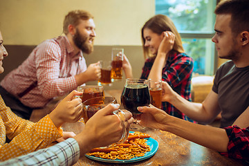 Image showing people, leisure, friendship and communication concept - happy friends drinking beer, talking and clinking glasses at bar or pub