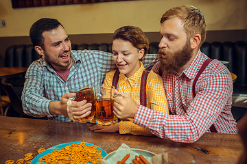 Image showing people, leisure, friendship and communication concept - happy friends drinking beer, talking and clinking glasses at bar or pub