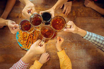 Image showing people, leisure, friendship and communication concept - happy friends drinking beer, talking and clinking glasses at bar or pub