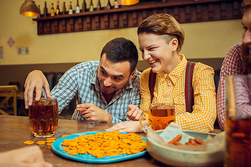 Image showing people, leisure, friendship and communication concept - happy friends drinking beer, talking and clinking glasses at bar or pub