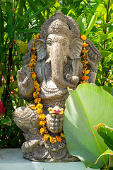 Image showing Garland of golden flowers draped around Ganesha