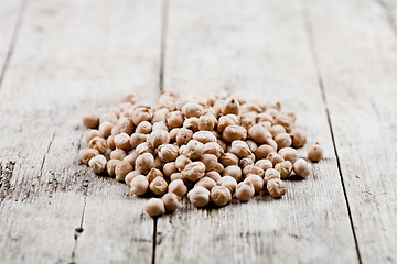 Image showing Dry raw organic chickpeas heap on rustic wooden table background
