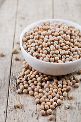 Image showing Fresh raw organic chickpeas in white ceramic bowl on rustic wood