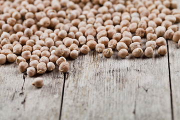 Image showing Dry raw organic chickpeas heap on rustic wooden table background