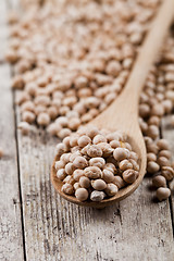 Image showing Fresh raw organic chickpeas in wooden spoon on rustic wooden tab