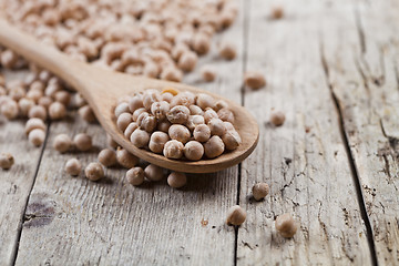 Image showing Fresh raw organic chickpeas in wooden spoon on rustic wooden tab