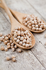 Image showing Fresh raw organic chickpeas in wooden spoons on rustic wooden ta