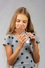 Image showing The ten-year-old girl joyfully looks at a chocolate bar