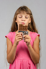 Image showing Eight-year-old girl with pleasure eats chocolate bar