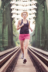 Image showing Active sporty woman running on railroad tracks.