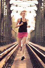 Image showing Active sporty woman running on railroad tracks.