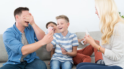 Image showing Happy young family playing card game at home.