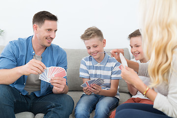 Image showing Happy young family playing card game at home.